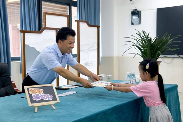 徐龍海用筆在《入學通知書》上認真寫下學生名字，起身將《入學通知書》遞還。金山小學供圖