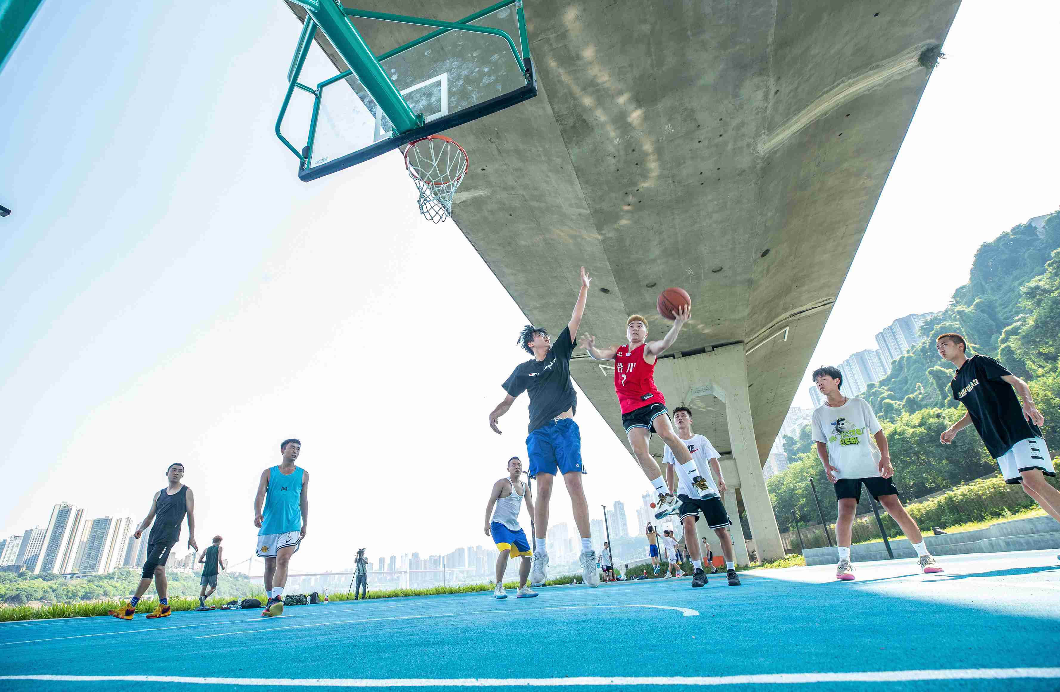 在渝中區黃沙溪大橋下，市民在長江邊的籃球場打球。何超攝