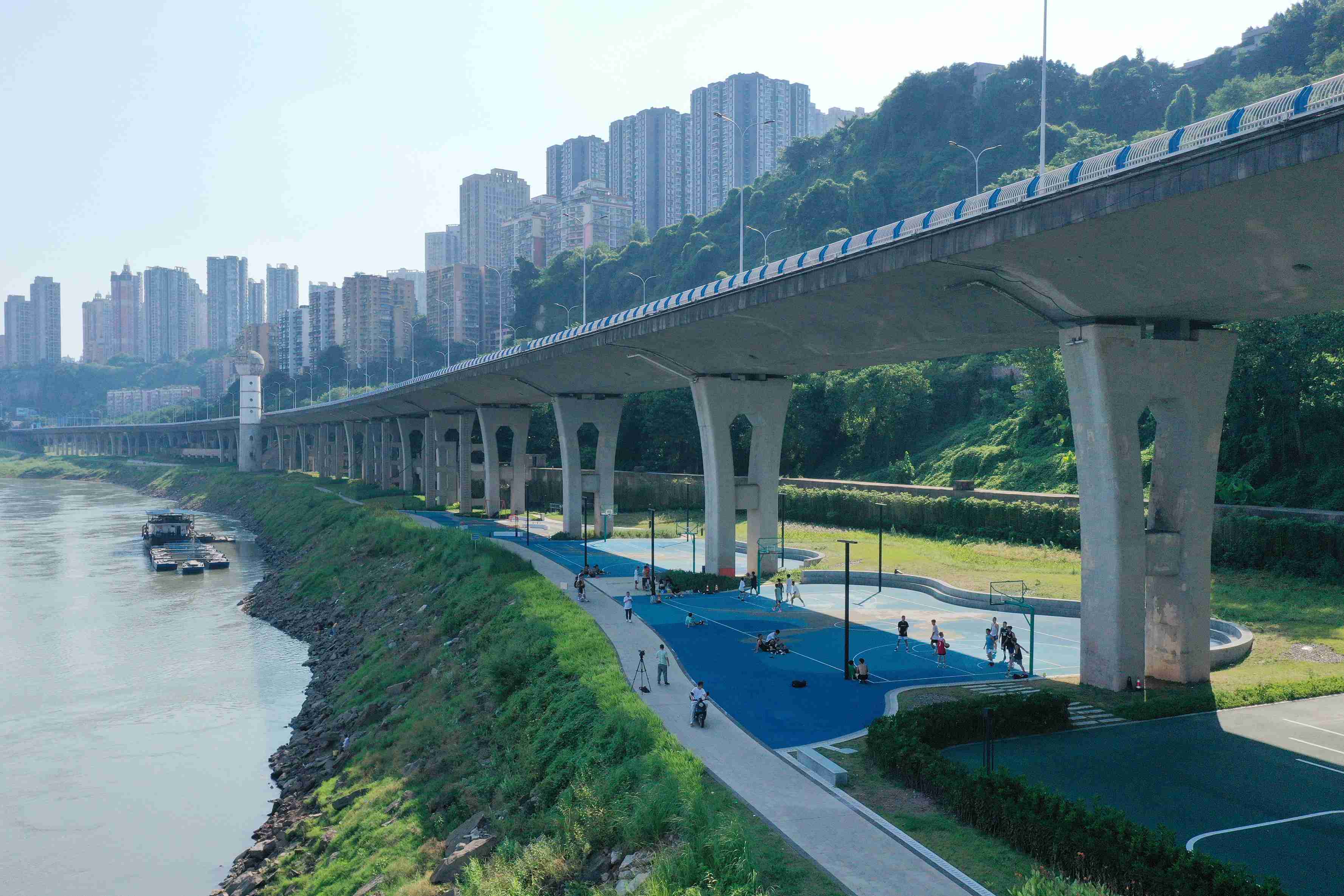 在渝中區黃沙溪大橋下，市民在長江邊的籃球場打球。何超攝