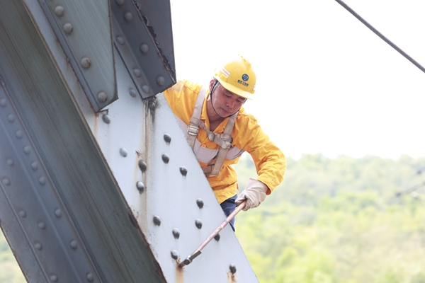 烈日下鮮志榮爬上鋼梁大橋檢查連接螺栓。晏濤攝