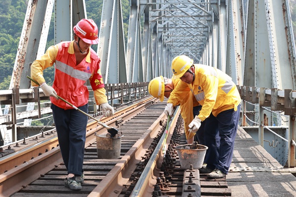 烈日下重慶工電段職工正在對襄渝鐵路北碚嘉陵江鋼梁大橋枕木扣件螺栓進行涂油。晏濤攝