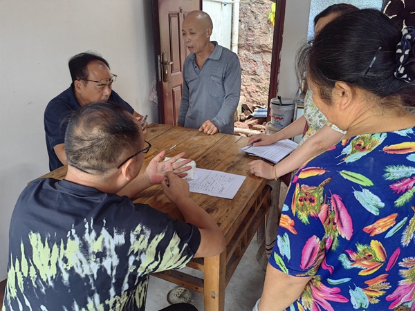 《信手拈來》。7月21日，重慶市二零八地質環境研究院有限公司勘察分院水文地質所所長兼潼南區駐守負責人王克峰與潼南區規劃和自然資源局梓潼所負責人米澤坤，在梓潼街道社區一戶農戶家里給戶主介紹如何做好房前屋后邊坡防治，王克峰隨手用筆在手上畫出邊坡輪廓。李鋒俊攝