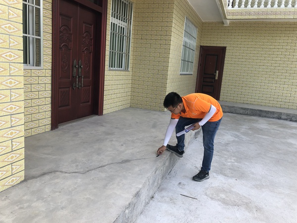 《清晨的野外巡查》。7月9日早上8時,黔江區駐守地質隊員潘笑天在五里鎮嚴家河進行巡查，現場調查記錄滑坡體上房屋的變形情況。  曹志遠攝