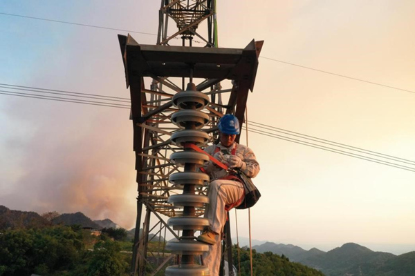 電力工人登塔開展搶修作業。李濤攝