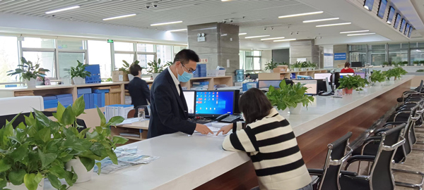 云陽縣行政審批大廳工作人員向建筑公司介紹分階段辦理施工許可證。云陽縣住建委供圖