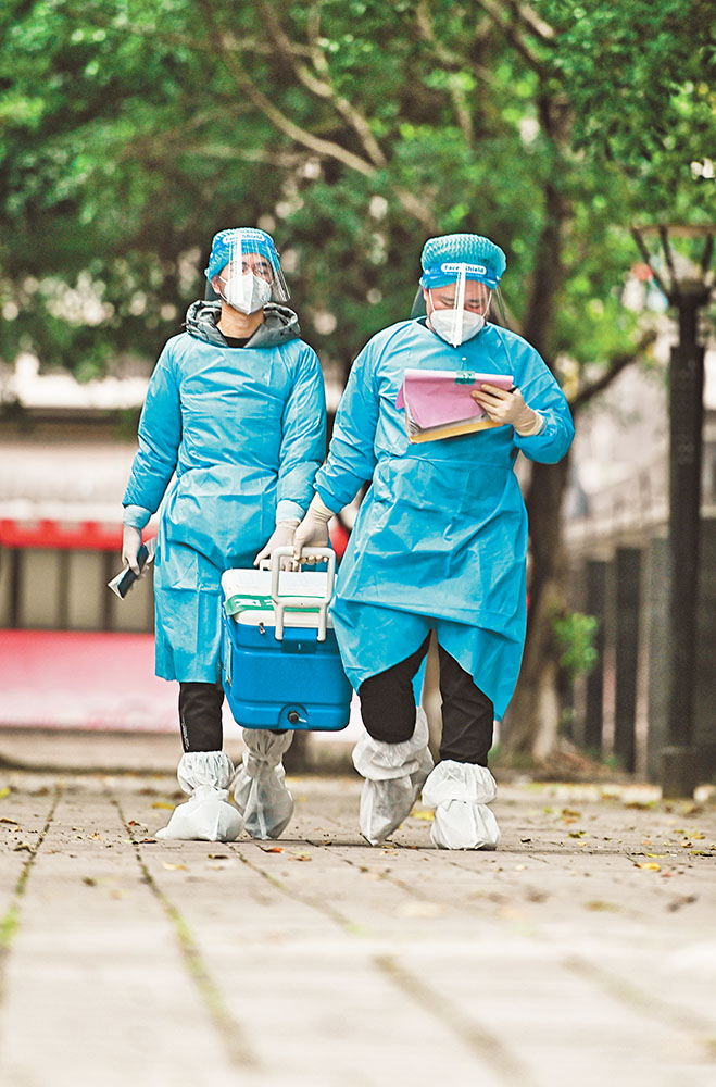 11月17日，北碚區朝陽街道河嘉村社區，“95后”志愿者何鑫(右)與張震在轉運核酸樣本。記者 萬難 攝 視覺重慶