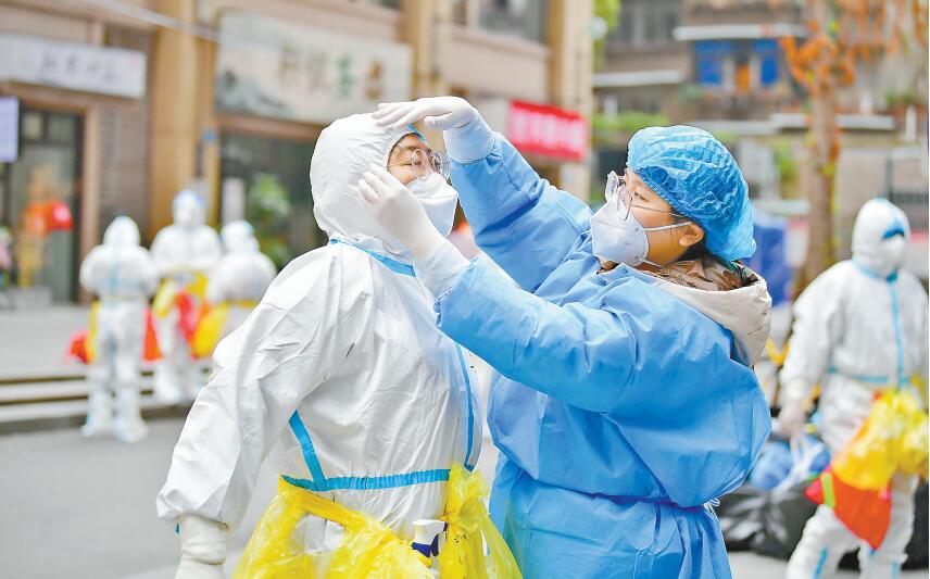 11月14日，九龍坡區楊家坪街道興勝路社區，志愿者陳曉宇（右）正在幫助醫護人員穿防護服。記者 鄭宇 通訊員 孫小剛 攝/視覺重慶