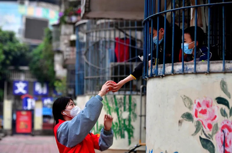 11月18日，南岸區長生橋鎮桃花橋社區移民小區，一位小朋友為正在小區巡查的大學生志愿者李江玲送上了一個蘋果。此次共有35名來自重慶多所高校的志愿者參加到長生橋鎮的疫情防控工作中。王雄 攝