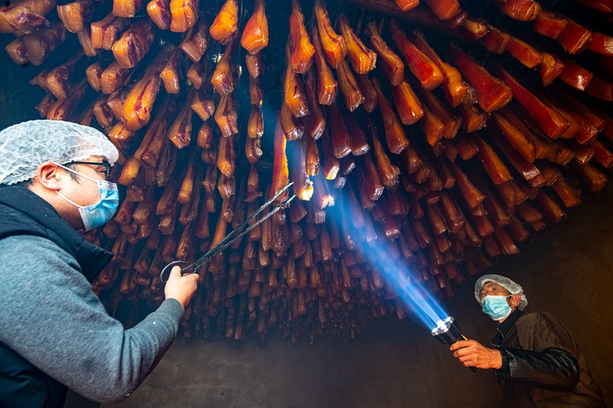 村民在烤臘腸。?冉孟軍攝