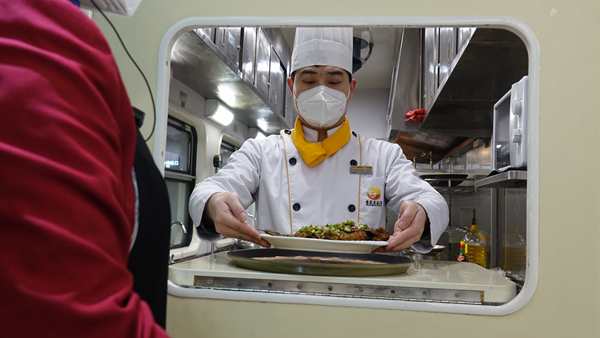 嚴鴻運端上做好的菜。李文航攝