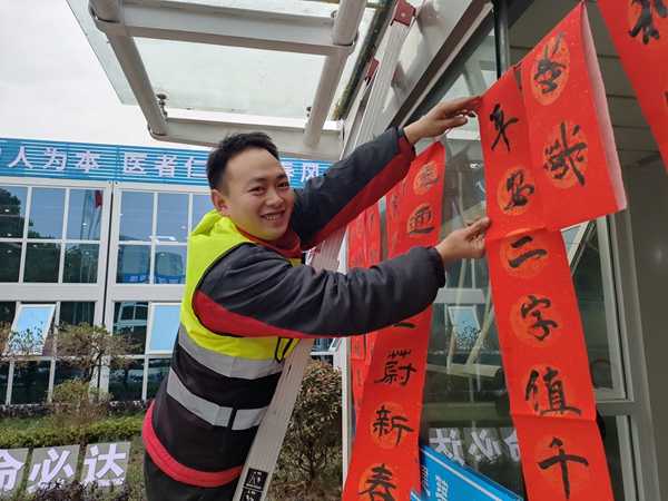 建設者將寫好的春聯掛上。