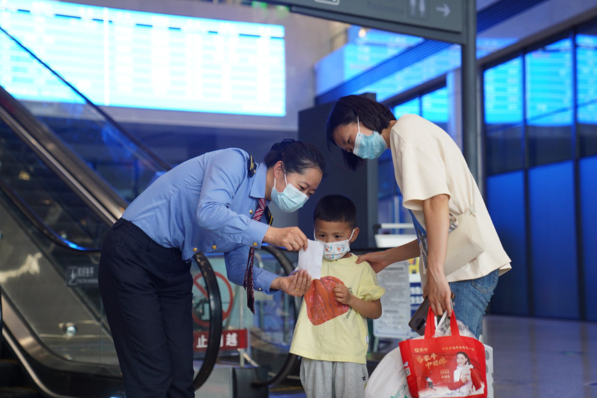重慶北站工作人員正在為小旅客講解行程提示單。汪亮攝