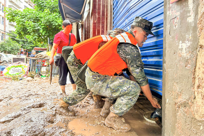 圖為武警官兵幫助受災群眾轉移物資。李東攝
