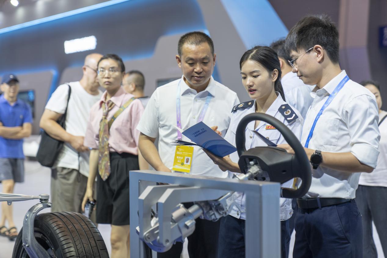 智博會現場，在重慶龍潤汽車轉向器有限公司展區，璧山區稅務人員正宣傳研發費用加計扣除等稅收優惠政策。郭睿攝