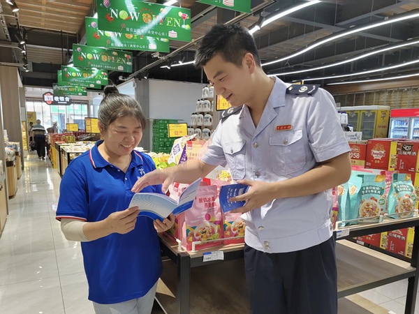 巫山縣稅務人員來到當地超市，送上批發零售業稅收優惠政策宣傳冊。羅超斌攝