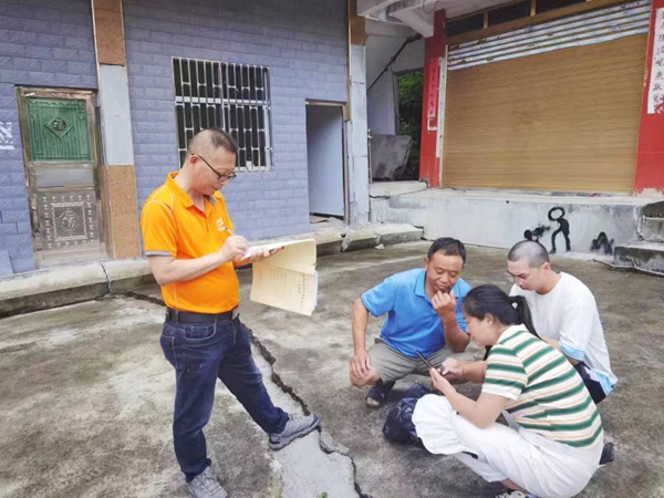 《現場指導》。7月19日，川東南勘察公司酉陽駐守地質工程師何登成（左一）在酉陽縣官清鄉百步巖滑坡查看群測群防記錄本，并指導監測人員進行監測工作。牛光猛攝