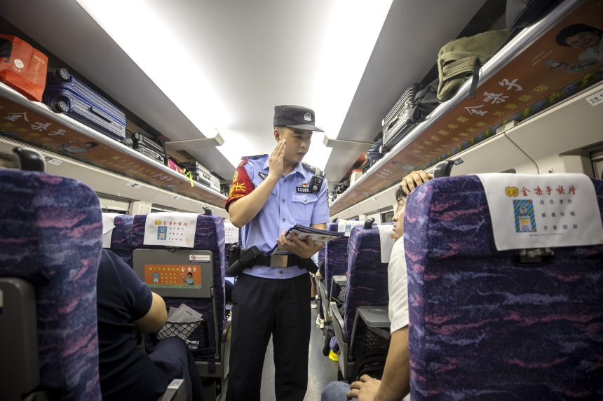 黃同川在列車上向旅客開展安全宣傳。胡勇攝