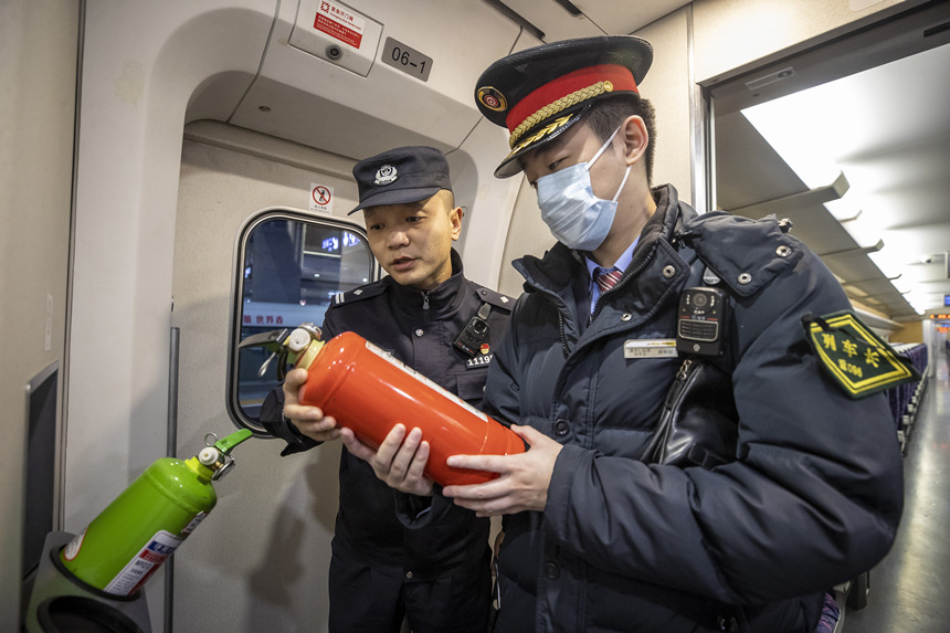彭聰（左一）在列車長的配合下，對列車配備的滅火器進行檢查。胡勇攝