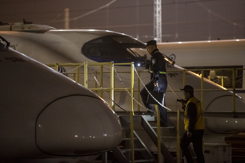 彭聰（左一）在重慶北動車所工作人員的配合下，爬上工作梯，對停放在存車場的列車進行巡視。胡勇攝