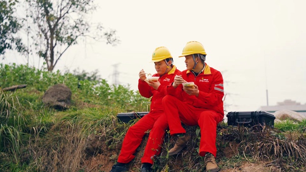 王睿和同事就地而坐吃著盒飯。國網重慶永川供電公司供圖