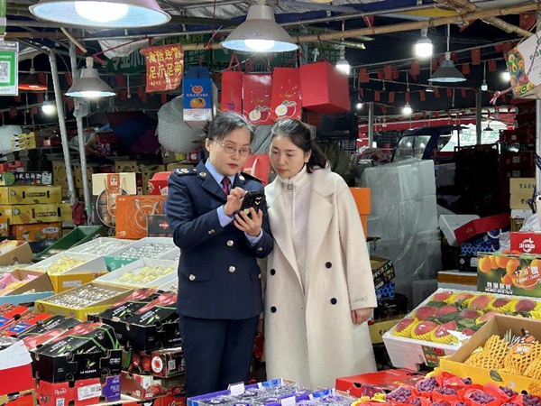 江津區稅務人員到雙福國際農貿城輔導商戶使用“農品慧”平臺。王露洪攝