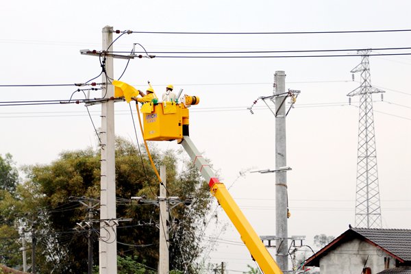電力工人正在做帶電立桿前的絕緣準備。朱芳攝