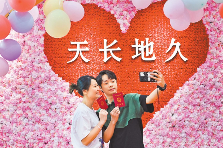 5月20日，渝北區婚姻登記處，新人正在拍照留影。當日，在該婚姻登記處，一對對新人排起了長隊?；橐龅怯浱幉扇‰娫掝A約、增加結婚登記窗口等舉措，保障結婚登記工作的順利開展。首席記者 龍帆 攝/視覺重慶