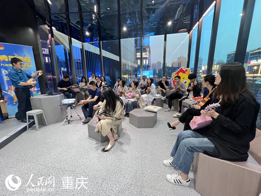 九龍坡區萬象書屋圓形劇場區里，學員們聚精會神聆聽老師講解尤克里里的構成。 人民網記者 胡虹攝