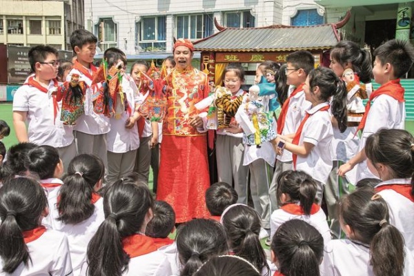 非遺傳承人張賢光給學生講解手掌木偶戲表演技藝。廣安區融媒體中心供圖