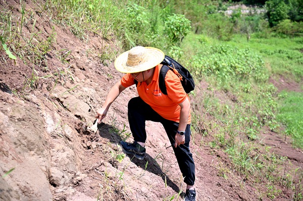 《地災防治工作一刻不能停歇》。8月6日，氣溫較高，107地質隊地質工程師黃元君仍奮戰在萬州區武陵鎮，在消落帶沿線測量巖壁的節理裂隙產狀。地災防治工作一刻不能停歇，氣溫雖高，地質工程師們卻克服困難，奮戰在山野之間。傅林攝