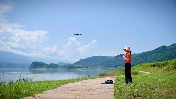 《巾幗有擔當》。8月6日，107地質隊地質工程師劉爽在萬州區武陵鎮江灣區域開展無人機航拍工作。傅林攝