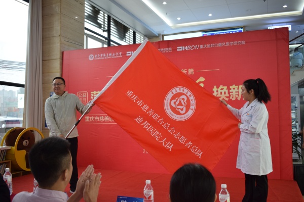 翁順春為迪邦醫院志愿者大隊授旗。重慶迪邦皮膚病醫院供圖