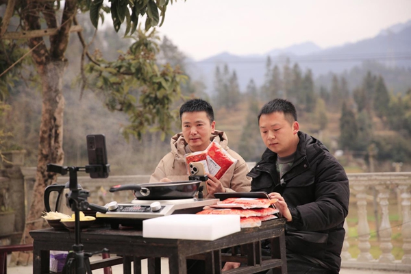 孫和發（左一）帶領返鄉創業大學生冉春生直播講解本地品牌“千丘原鄉”火鍋底料。謝紹春攝