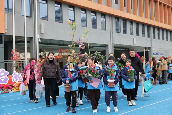 學生和家長歡歡喜喜“認養”苗木。秦廷富攝