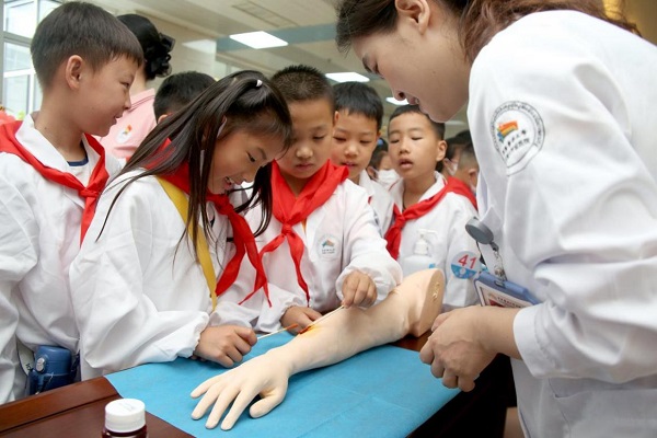 往屆活動中，小醫生們在醫護人員的指導下學習傷口消毒及包扎。重醫附屬大學城醫院供圖