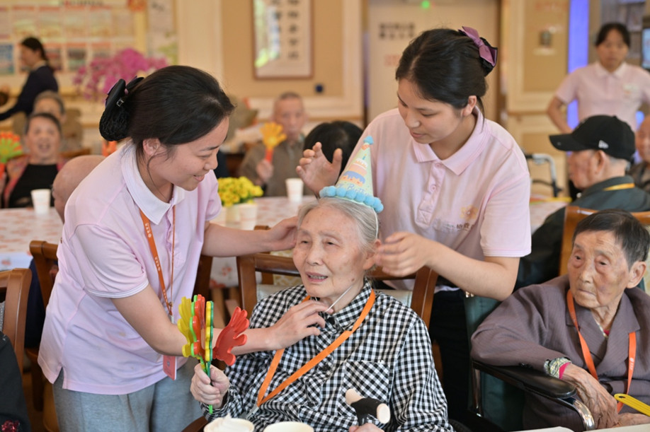 養老機構工作人員為壽星老人們戴上生日帽，情暖老人心。程佩玉攝