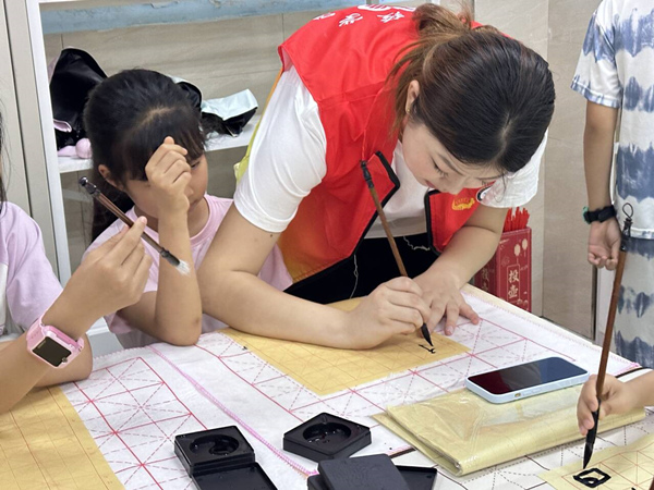 志愿者幫助孩子們在墨香中感受傳統文化魅力。唐彬貴攝