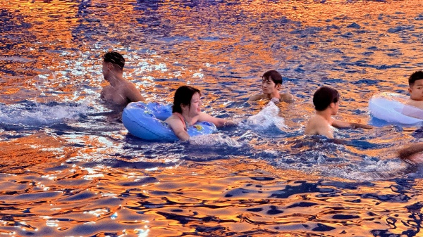 游客在晚霞映照的水面戲水。景區供圖