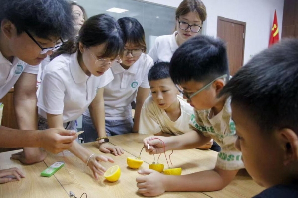 踐行團成員指導小朋友進行水果發電實驗。重慶電力高等?？茖W校供圖