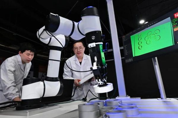 中科搖櫓船研發人員在對3D結構光相機配合機械臂抓取工件的場景進行優化調試。中科搖櫓船供圖