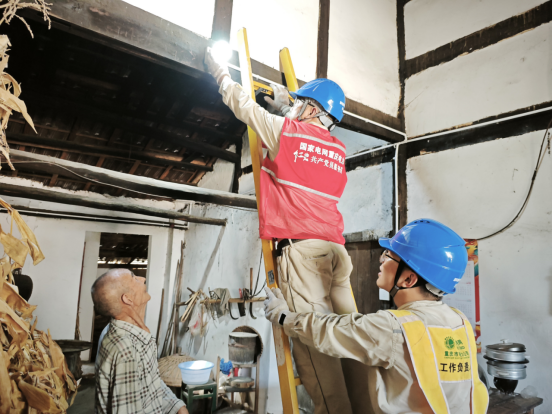 工作人員為老人整理線路并安裝節能燈。鐘雪攝