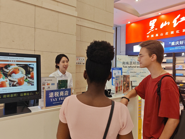 在解放碑的重慶環球金融中心離境退稅服務臺，工作人員為來自俄羅斯和西非多哥的游客介紹離境退稅“即買即退”服務。徐佑君攝