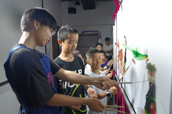 表演老師指導孩子們使用皮影道具。西部航空供圖