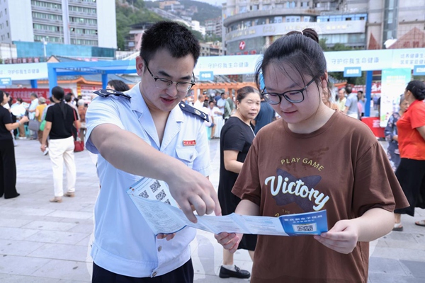奉節縣稅務人員在公平競爭政策宣傳活動現場向市民宣傳納稅信用管理相關政策。孫艷嬌攝