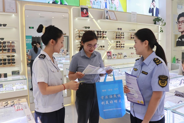 在綦江區萬達商圈，稅務人員走訪商圈內的店鋪，宣傳講解稅法條款。任韻西攝