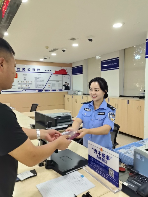 王先生從輔警手中接過身份證和港澳通行證。南岸區公安分局供圖